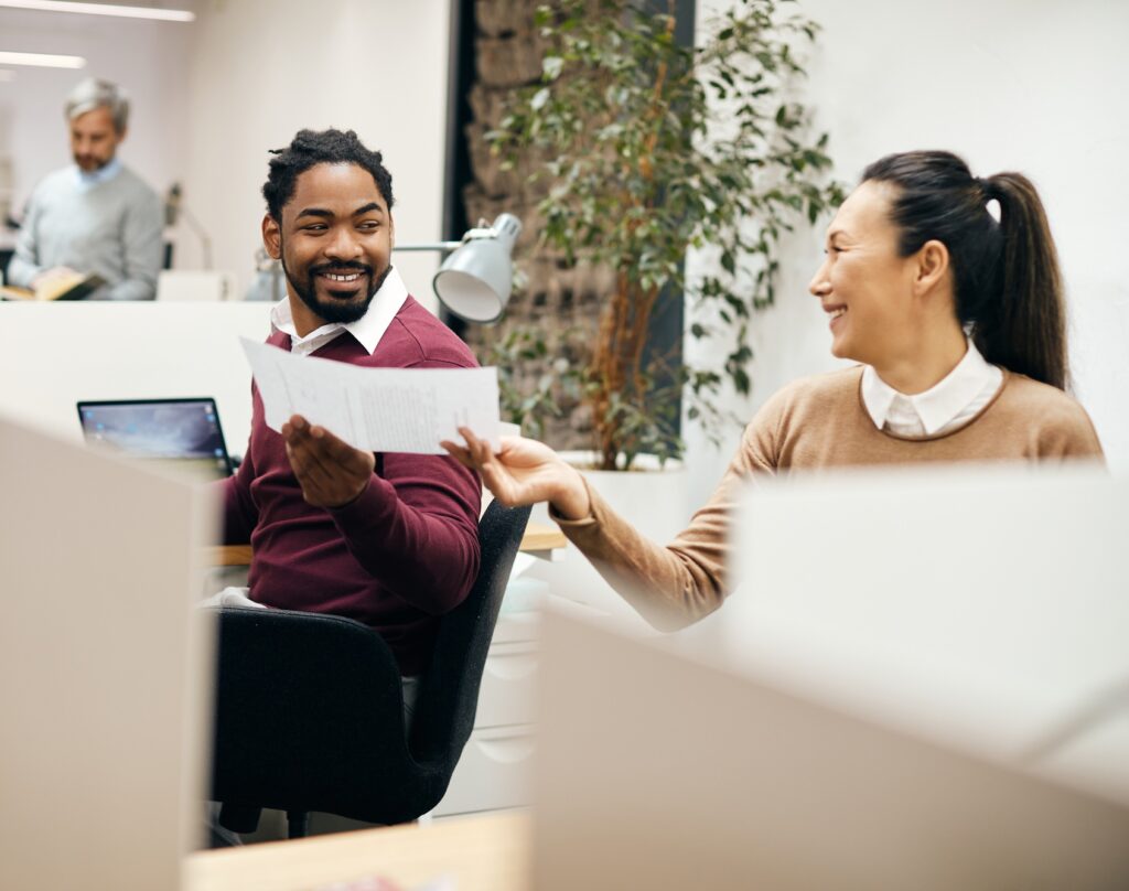 Happy colleagues cooperating while working on business reports in the office.